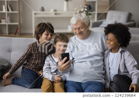 Elderly grandfather watch education video on smartphone with multiethnic grandsons 124239664