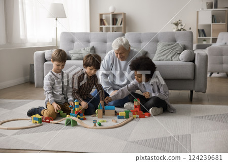 Aged grandpa play with construction set with three multiracial grandsons 124239681