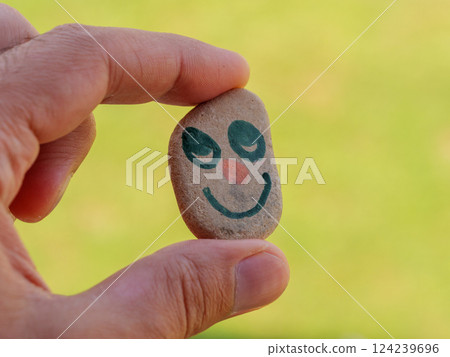 Holding a stone with a smiling face design in natural surroundings Holding a stone with a smiling face design in natural surroundings 124239696