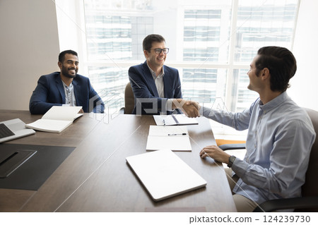 Business partners shaking hands seated at conference desk 124239730