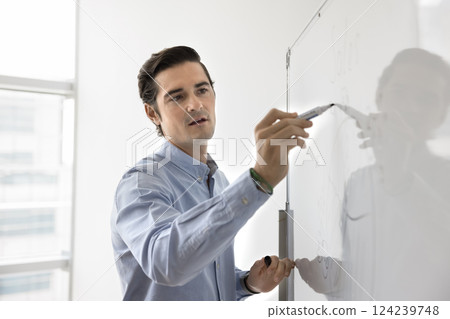 Hispanic businessman or corporate trainer presenting sales data on whiteboard 124239748