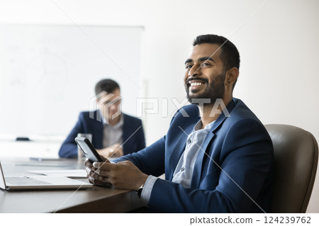 Smiling Indian businessman getting happy by received news in sms Smiling Indian businessman getting happy by received news in sms 124239762