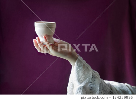A hand in ancient clothing holds a clay bowl 124239956