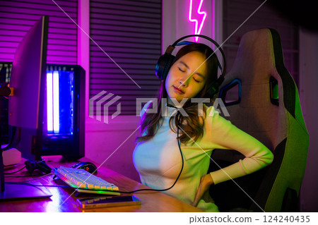 Asian woman gamer playing video game on gaming pc computer due to sitting long time she stressed suffering for backache, female streaming games online at home holding back her problem Asian woman gamer playing video game on gaming pc computer due to sitting long time she stressed suffering for backache, female streaming games online at home holding back her problem 124240435