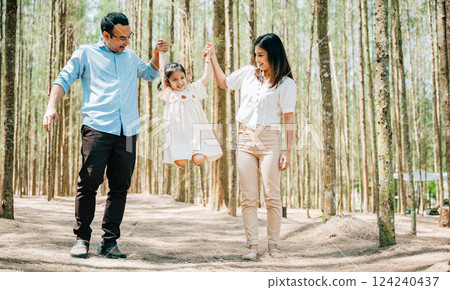 Full length portrait Asian family enjoying a peaceful walk through park forest outdoor holding hands spending time together on weekend, Happy father mother and daughter, Family day memory on holiday 124240437