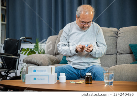 Asian worried senior man with medicine pills he read on see how to take pills before taking, old man buy herbal self cure Rx pill online from pharmacy, home isolation, Medical service concept 124240486