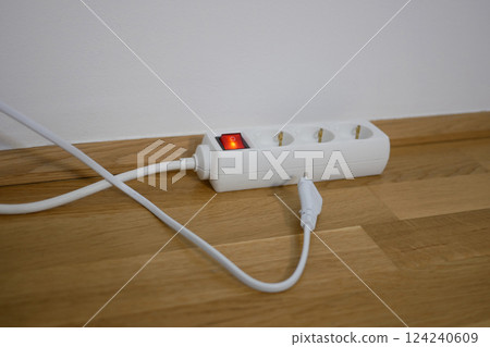 The electric cable is lying next to power strip socket extension cord The electric cable is lying next to power strip socket extension cord 124240609