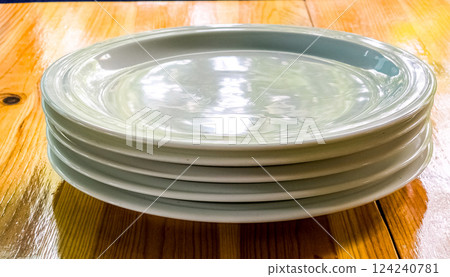 Several white empty plates on a wooden table. Several white empty plates on a wooden table. 124240781