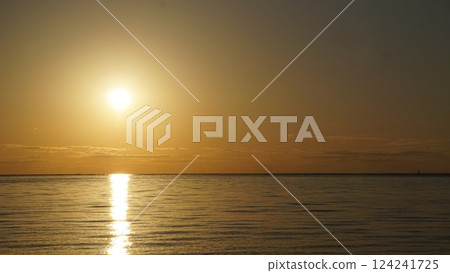 Sunset, the setting sun illuminating the water's surface. 124241725
