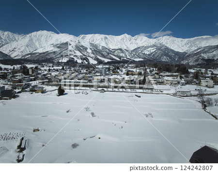 A magnificent view of the Hakuba mountain range, Happo-one ski resort, and Hakuba village from Tenjinzaka. Hakuba village, Nagano prefecture (aerial shot by drone) A magnificent view of the Hakuba mountain range, Happo-one ski resort, and Hakuba village from Tenjinzaka. Hakuba village, Nagano prefecture (aerial shot by drone) 124242807