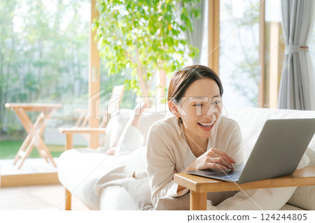 一個女人在沙發上使用電腦 一個女人在沙發上使用電腦 124244805