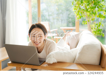 一個女人在沙發上使用電腦 一個女人在沙發上使用電腦 124244935