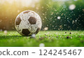 Soccer ball on a grassy field, partially covered in dirt, with grass and soil particles flying around	 124245467