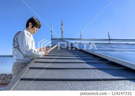 A man checking the progress of roof repair work on a detached house A man checking the progress of roof repair work on a detached house 124247332