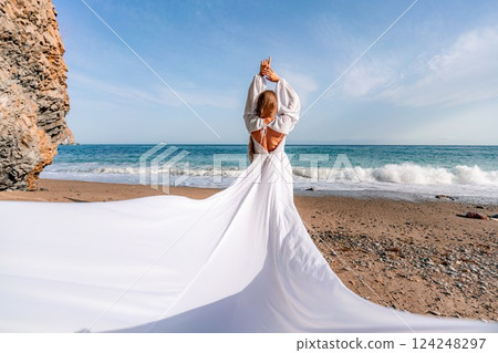 Woman beach white dress flying on Wind. Summer Vacation. A happy woman takes vacation photos to send to friends. Woman beach white dress flying on Wind. Summer Vacation. A happy woman takes vacation photos to send to friends. 124248297
