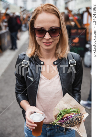 Beautiful young woman holding delicious organic salmon vegetarian burger and homebrewed IPA beer on open air beer an burger urban street food festival in Ljubljana, Slovenia Beautiful young woman holding delicious organic salmon vegetarian burger and homebrewed IPA beer on open air beer an burger urban street food festival in Ljubljana, Slovenia 124248968