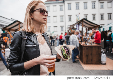 Close up of woman hands holding delicious organic salmon vegetarian burger and homebrewed IPA beer on open air beer an burger urban street food festival in Ljubljana, Slovenia Close up of woman hands holding delicious organic salmon vegetarian burger and homebrewed IPA beer on open air beer an burger urban street food festival in Ljubljana, Slovenia 124249015