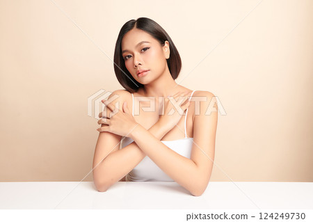 A beautiful young Asian woman with clean, fresh skin against a beige background. Skincare, facial treatment, cosmetology, beauty, and spa. An elegant portrait of an Asian woman. 124249730