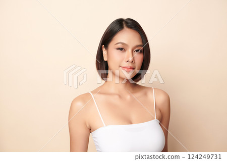 A beautiful young Asian woman with clean, fresh skin against a beige background. Skincare, facial treatment, cosmetology, beauty, and spa. An elegant portrait of an Asian woman. 124249731
