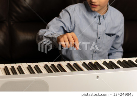 Boy pointing at key on the keyboard while playing. Boy pointing at key on the keyboard while playing. 124249843