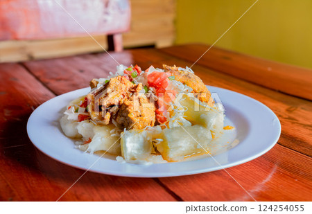 Traditional Chancho dish with Yuca. Nicaraguan pork with yucca served on wooden table Traditional Chancho dish with Yuca. Nicaraguan pork with yucca served on wooden table 124254055