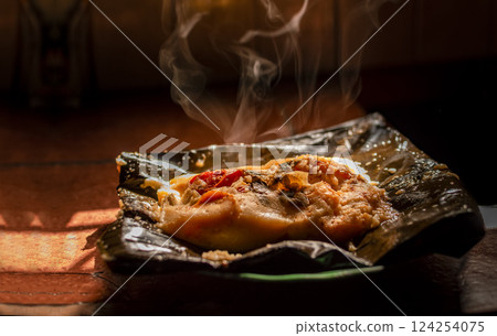 Side view of Nicaraguan Nacatamal ready to eat, Typical Nicaraguan Nacatamal freshly made served on the table, Homemade Nicaraguan Nacatamal, Traditional Nacatamal served in banana leaf 124254075