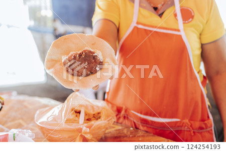 Hand of a vendor showing traditional raw pupusa. Elaboration of traditional pupusas, Preparation of the dough for traditional Nicaraguan pupusas 124254193