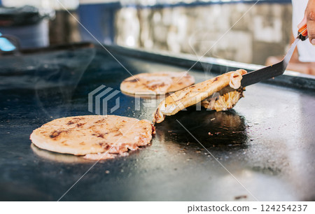Spatula taking a traditional cheese pupusas on the grill, Close up of traditional artisan grilled pupusas. Traditional Nicaraguan pupusas with melted grilled cheese 124254237