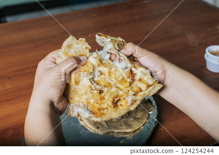 View of hands dividing delicious Salvadoran pupusas on wooden table. Concept of traditional handmade pupusas, Hands dividing delicious Nicaraguan pupusa on the table View of hands dividing delicious Salvadoran pupusas on wooden table. Concept of traditional handmade pupusas, Hands dividing delicious Nicaraguan pupusa on the table 124254244