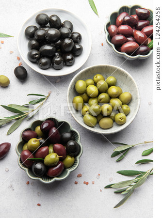 Assorted olives in decorative bowls on white surface Assorted olives in decorative bowls on white surface 124254258