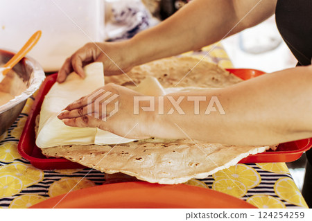 Hands preparing the traditional Nicaraguan Quesillo, Preparation of Traditional Nicaraguan Quesillo. Person making delicious Nicaraguan cheese. Traditional cheese with pickled onion. 124254259