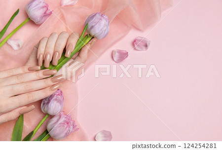 Woman hands with nude manicure holding pink tulips on pink background Woman hands with nude manicure holding pink tulips on pink background 124254281