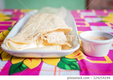 Close up of a Nicaraguan quesillo served on wooden table. Top view of Nicaraguan Quesillo on a plate served on wooden table. Delicious traditional Nicaraguan quesillo served on wooden table Close up of a Nicaraguan quesillo served on wooden table. Top view of Nicaraguan Quesillo on a plate served on wooden table. Delicious traditional Nicaraguan quesillo served on wooden table 124254294