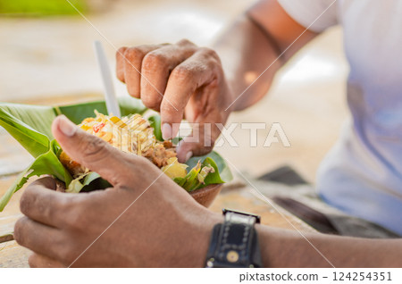 Close-up of a person eating vigoron, person eating vigoron on a wooden table 124254351