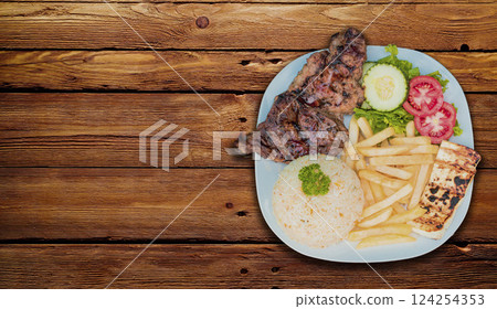 Roasted chicken dish with gallo pinto and pico de gallo on wooden table, Top view of roasted chicken dish with rice t french fries served on wooden background, Concept of typical Nicaraguan food 124254353