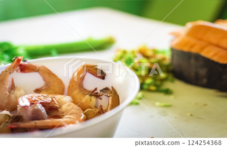 Bowl of raw shrimp on the table with vegetables out of focus background, Raw shrimp on the table with vegetables out of focus background 124254368