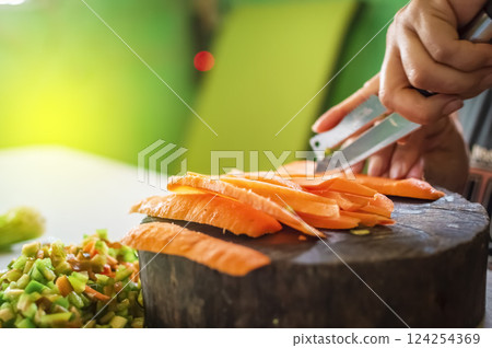 Close up of hands cutting pieces of carrot on homemade wooden base , Hands cutting carrot on homemade log with copy space 124254369