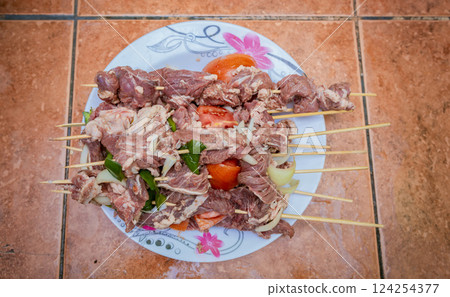 Raw beef skewers on a plate. Preparation of raw beef skewers. Fresh and raw beef skewers on a plate. Close up of raw beef meat skewers with ingredients 124254377
