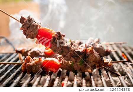 Grilled meat skewers. Close up of homemade roast beef on the grill, Roast beef skewer with tomato. Details of a delicious homemade roast beef 124254378