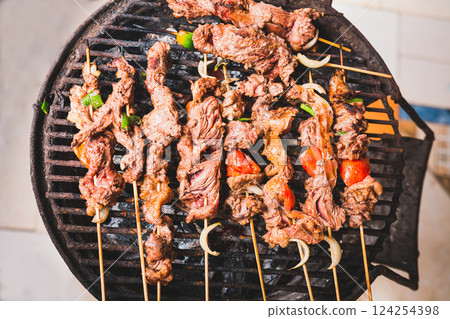Homemade roast meat skewers on charcoal grill. Charcoal roasted meat skewers. Top view of meat roasted on a grill 124254398