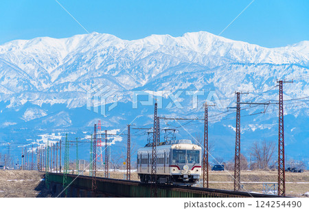 Toyama Chiho Railway and the snowy Tateyama mountain range 124254490