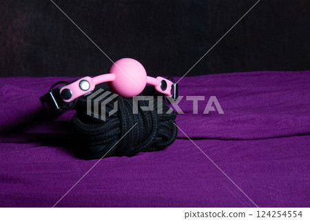 Bdsm outfit. Bondage and Gag ball on the purple bedsheet. Adult sex games. Kinky lifestyle. Bdsm outfit. Bondage and Gag ball on the purple bedsheet. Adult sex games. Kinky lifestyle. 124254554