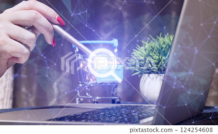 Digital workspace for real estate search and e-commerce with hand using stylus on shopping cart icon, laptop with network graphics 124254608