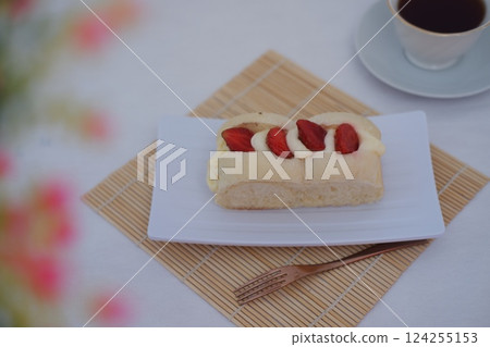 a soft bread roll topped with creamy custard and slices of fresh strawberries 124255153