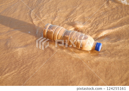 plastic bottle lying on a sandy beach 124255161