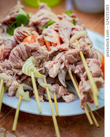 Close up of raw beef meat skewers with ingredients. Fresh and raw beef skewers on a plate. Raw beef skewers on a plate. Preparation of raw beef skewers. 124255365