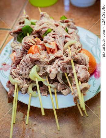 Raw beef skewers on a plate. Close up of raw beef meat skewers with ingredients. Fresh and raw beef skewers on a plate. Preparation of raw beef skewers. 124255366