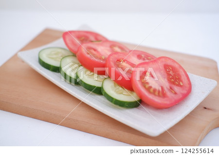 Cucumber and tomato slices on a plate on a white background 124255614