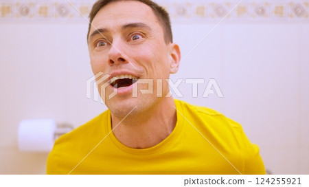 Man feeling relieved while sitting on toilet in bathroom Man feeling relieved while sitting on toilet in bathroom 124255921