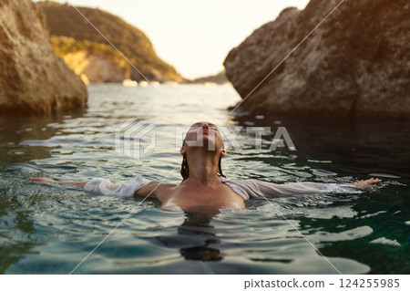 Nude sexy woman in water at sunset. Beautiful blonde woman with short wet hair and big breasts, art portrait in sea Nude sexy woman in water at sunset. Beautiful blonde woman with short wet hair and big breasts, art portrait in sea 124255985